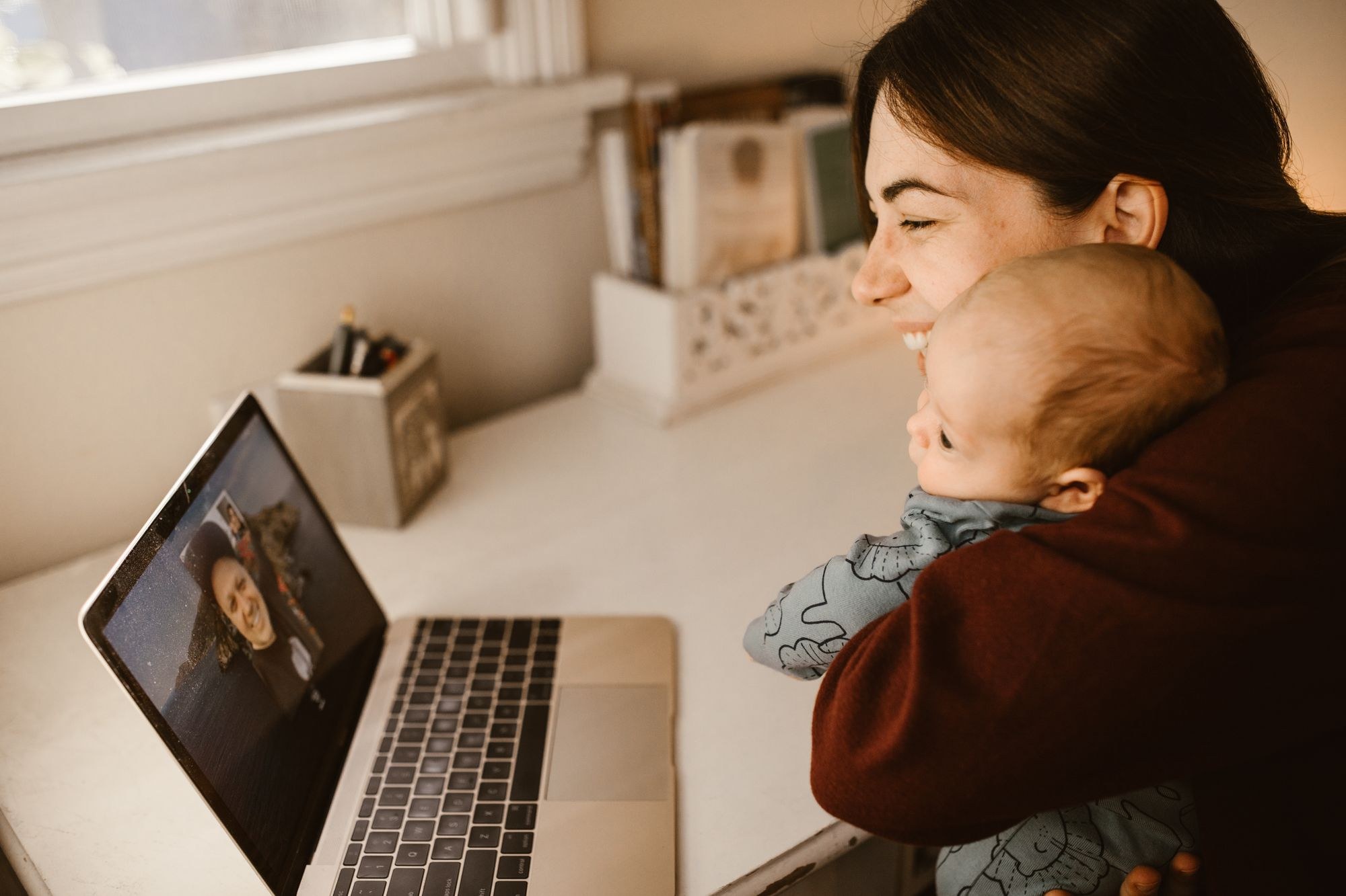 Mãe com o bebê no colo em consulta por vídeo no notebook